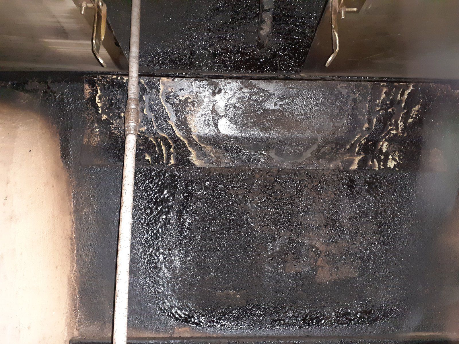 Intérieur noirci d'une grille d'aération ou d'un conduit métallique par accumulation de suie et de résidus