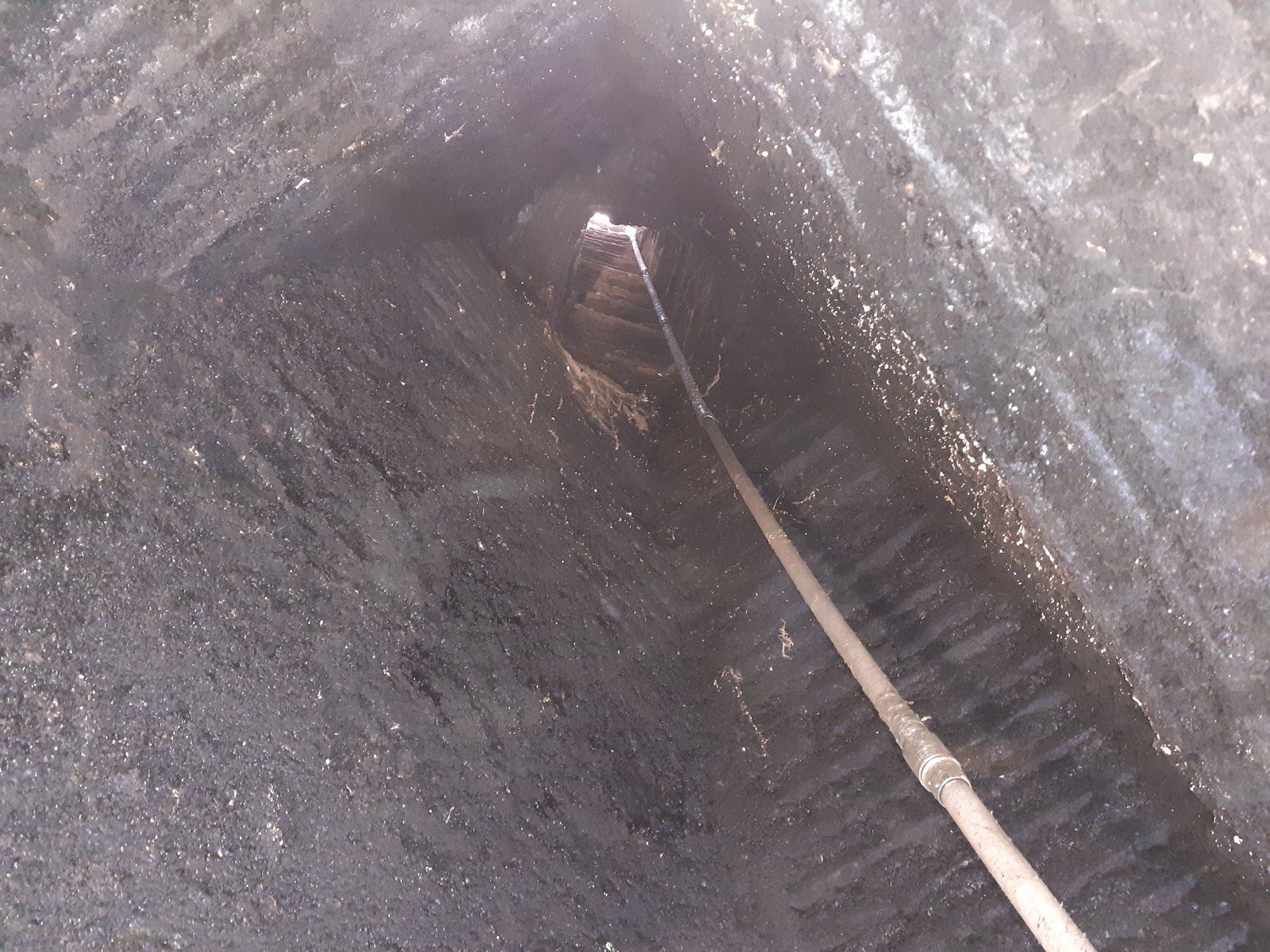 Gros plan sur l'intérieur d'un tube ou d'un tuyau sombre et étroit, avec une fine tige qui s'étend à l'intérieur.