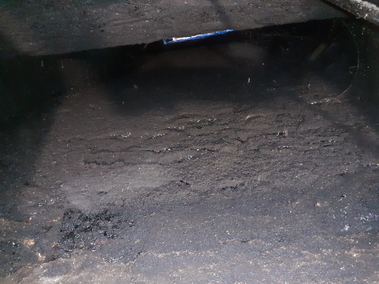 Tunnel sombre et caillouteux ou vide sanitaire avec une petite lumière bleue au loin