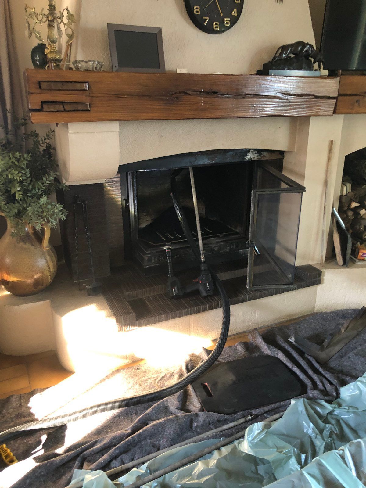 Cheminée endommagée avec des débris noirs effondrés et des objets éparpillés sur le foyer dans un salon