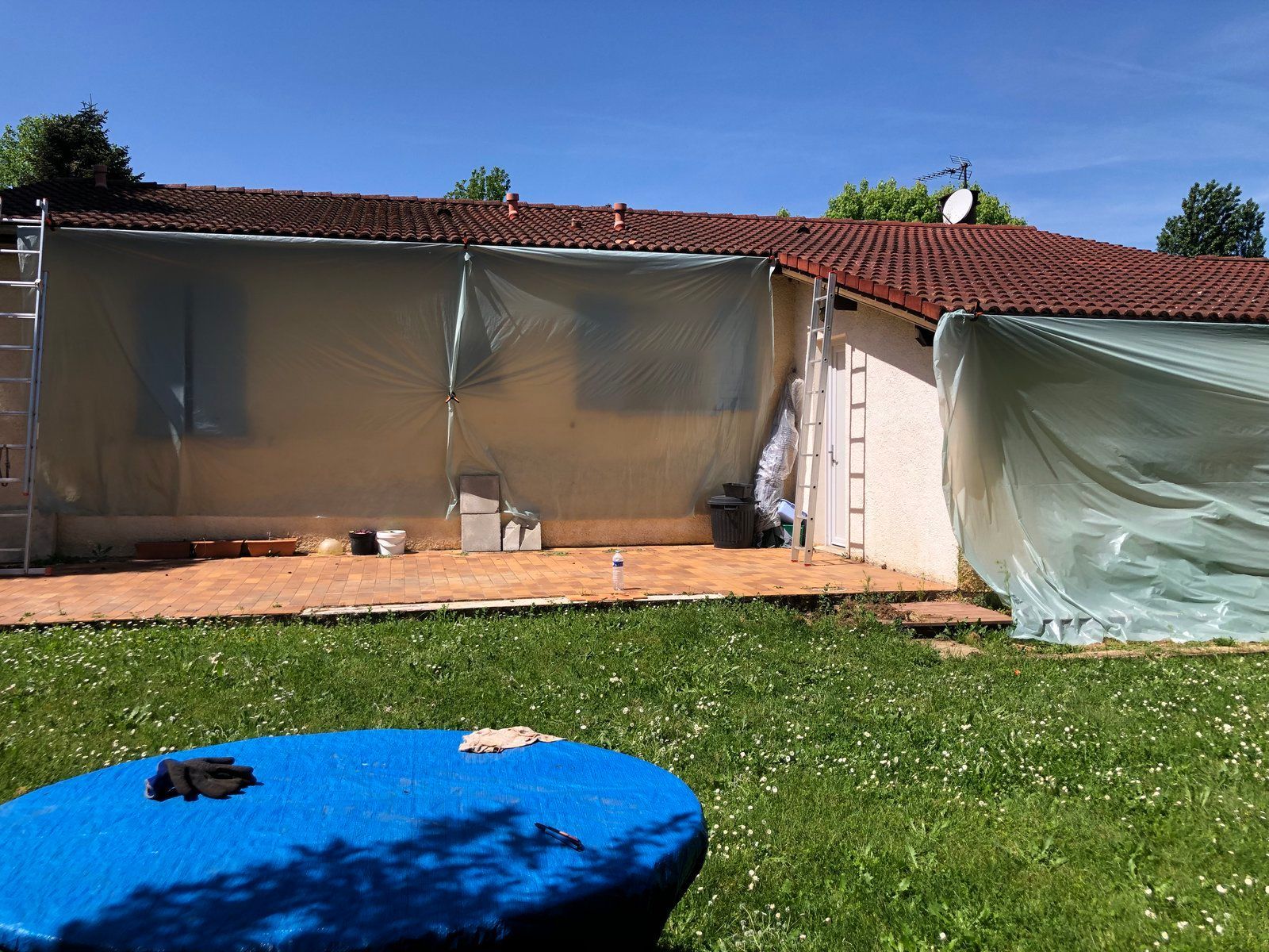 Terrasse arrière avec véranda, toit de tuiles rouges et trampoline bleu au premier plan