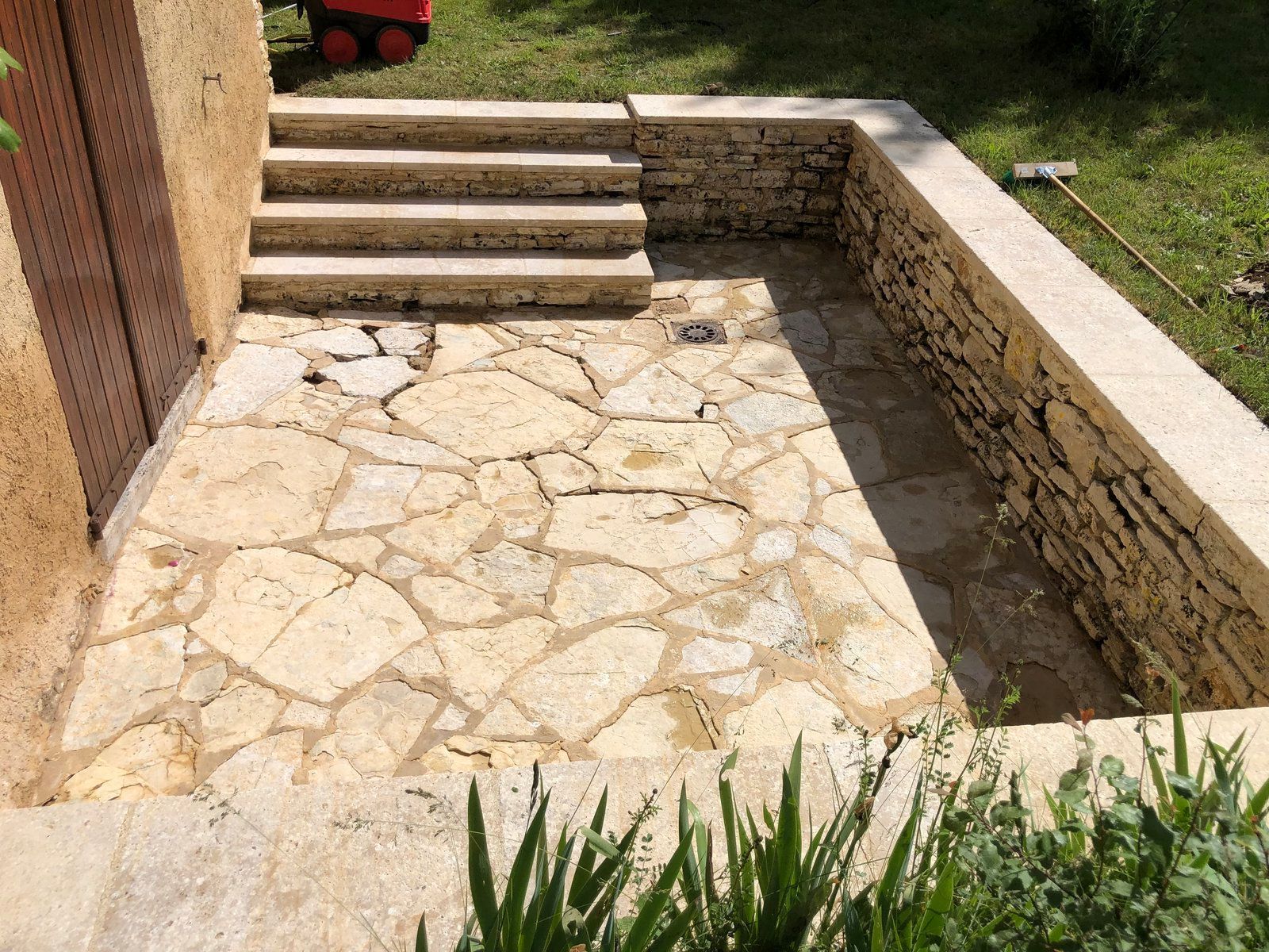 Terrasse en pierre avec marches et muret bas donnant sur une pelouse