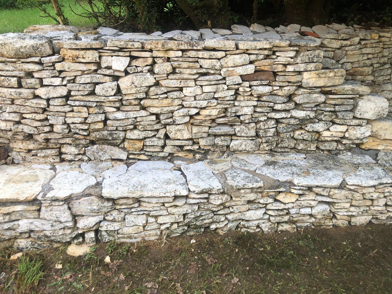 Mur de pierre avec des pierres empilées grossièrement et du mortier blanc dans un cadre extérieur