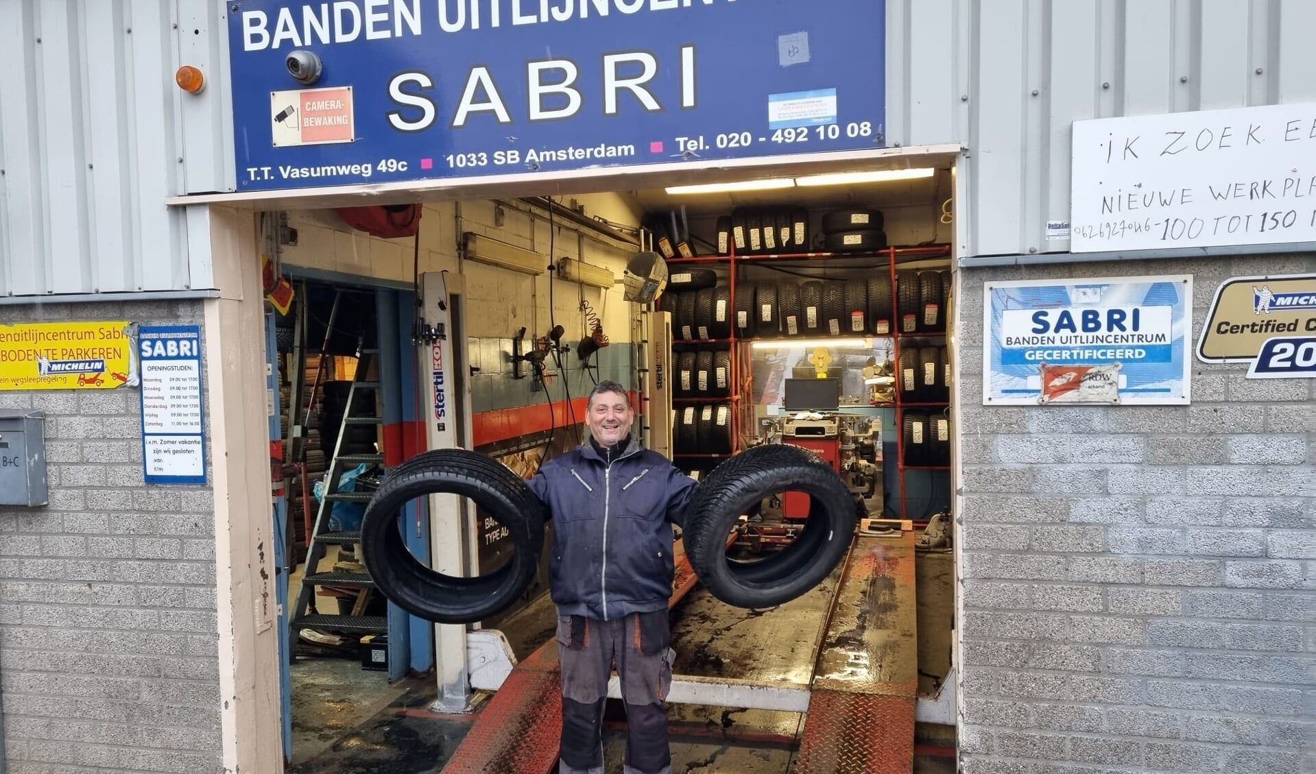 Een man met banden voor de bandenwinkel 