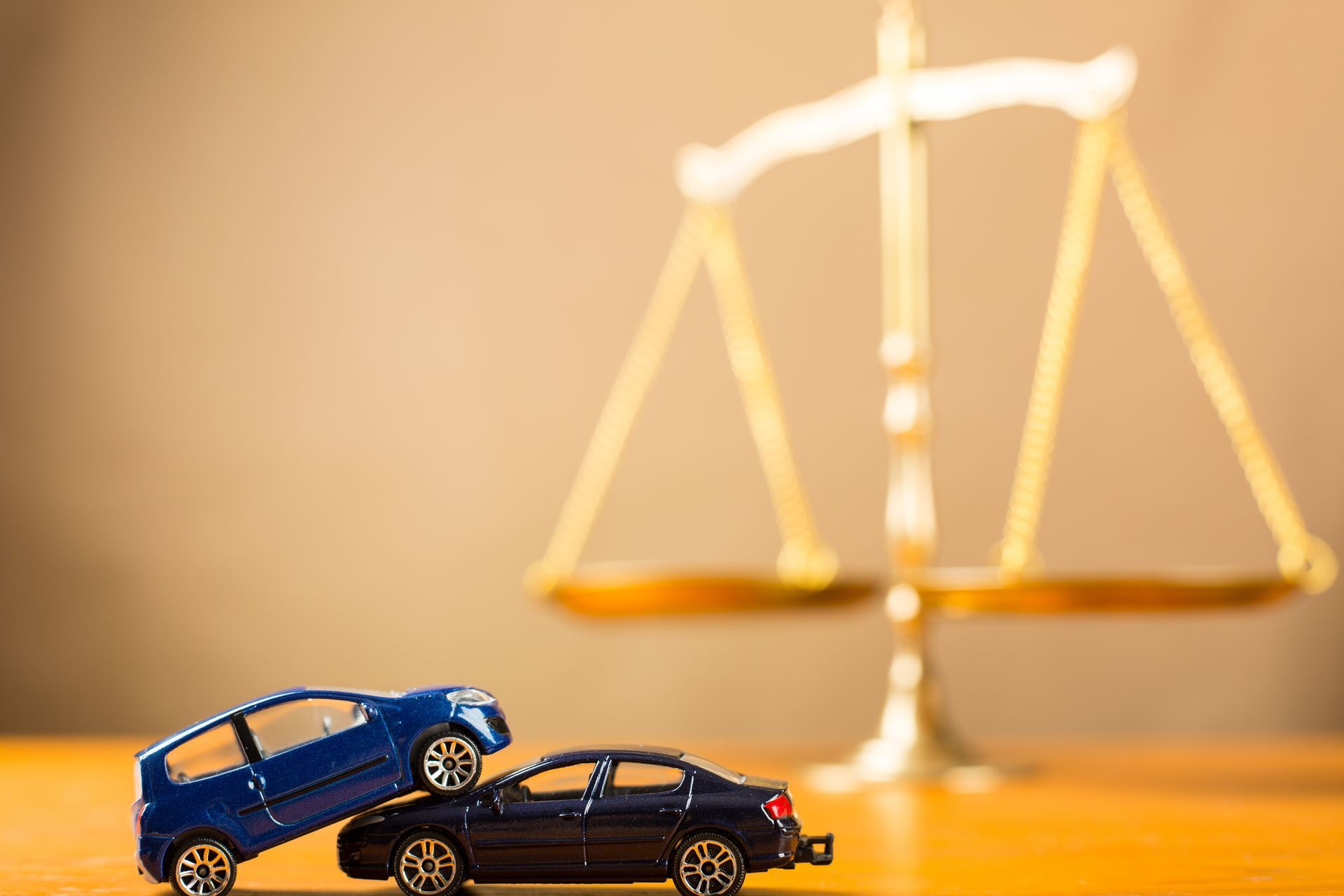 A blue toy car atop a black justice scale behind, symbolizing accident law and fairness.