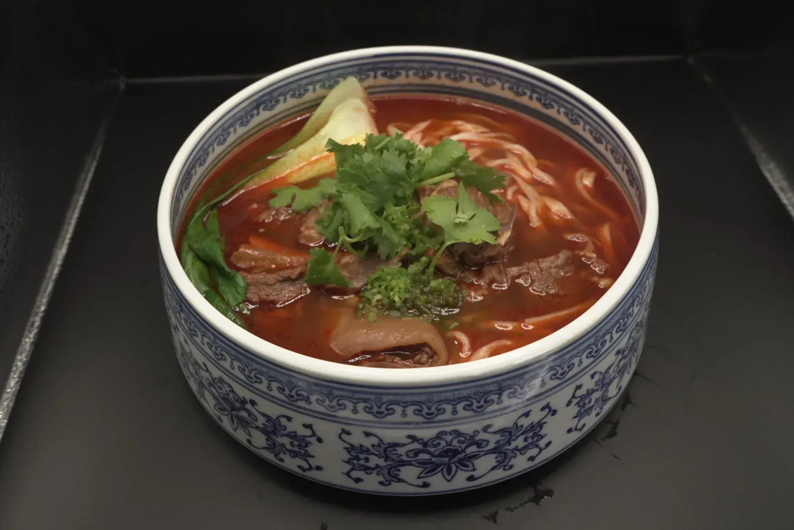 Bowl of red soup topped with cilantro, in a blue-and-white patterned bowl