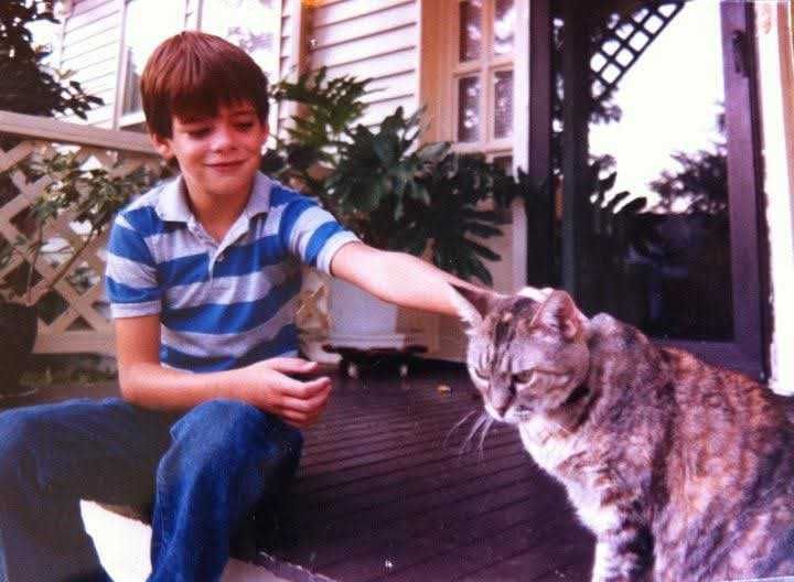 Childhood photo of Coming Home co-founder Chance Glasco sitting on a porch and petting a cat.