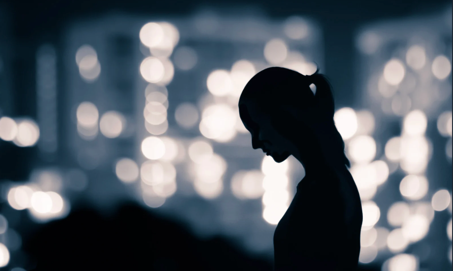Silhouette of a person alone against blurred city lights representing emotional struggle and isolati