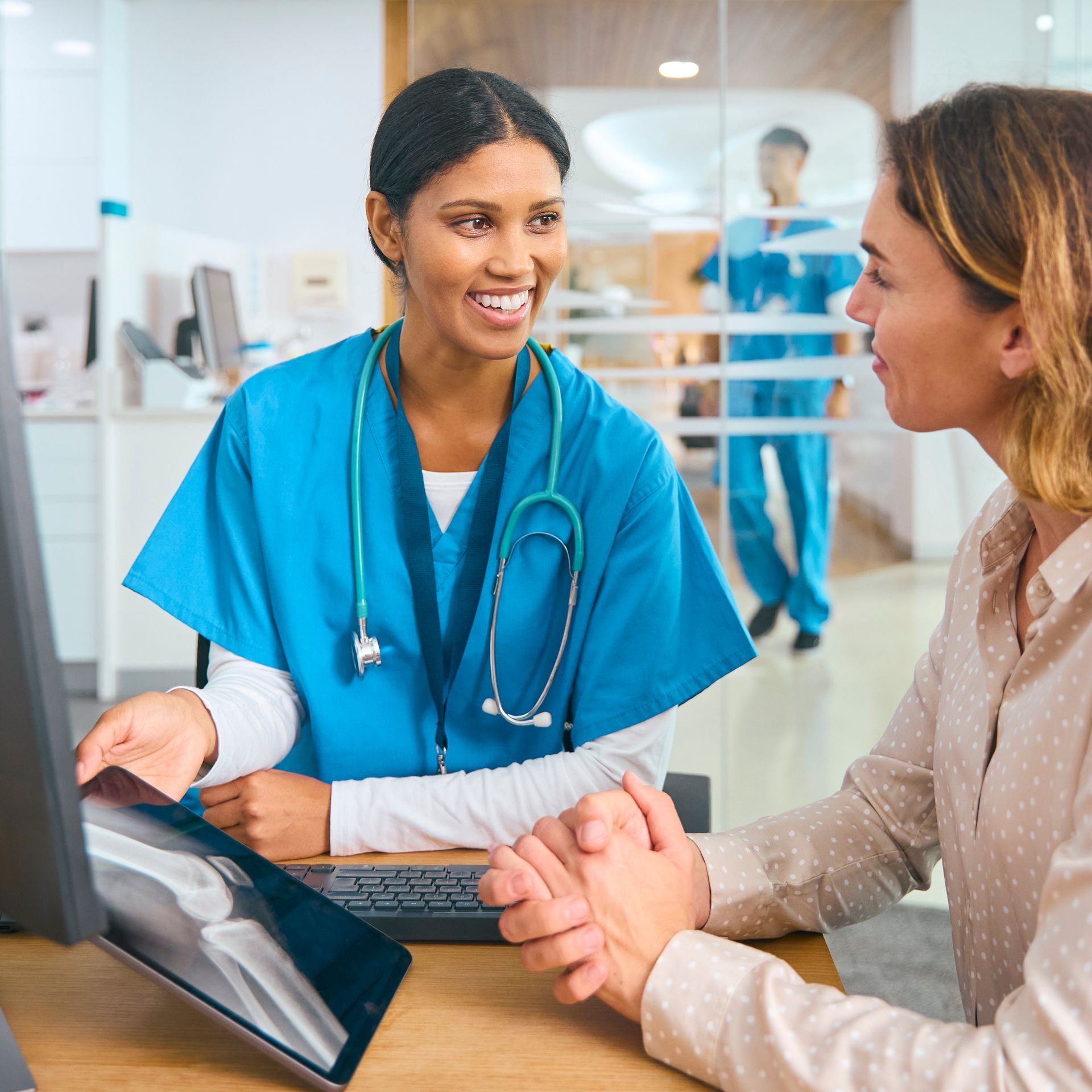 A nurse is talking to a patient in front of a computer.