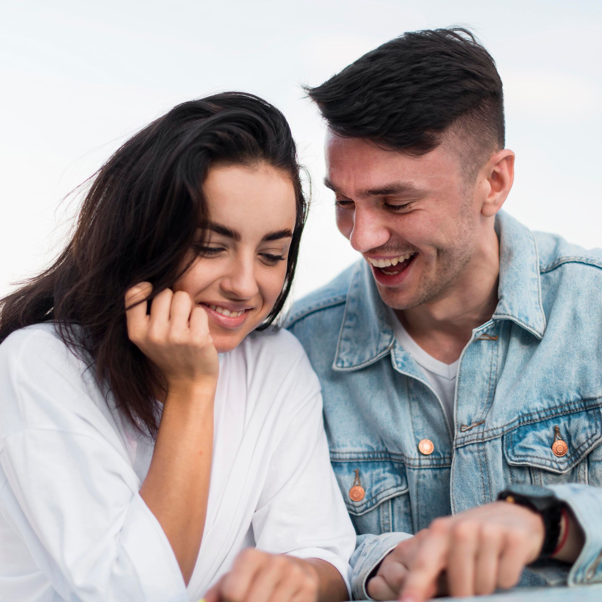 A man and a woman are looking at a laptop together and smiling.