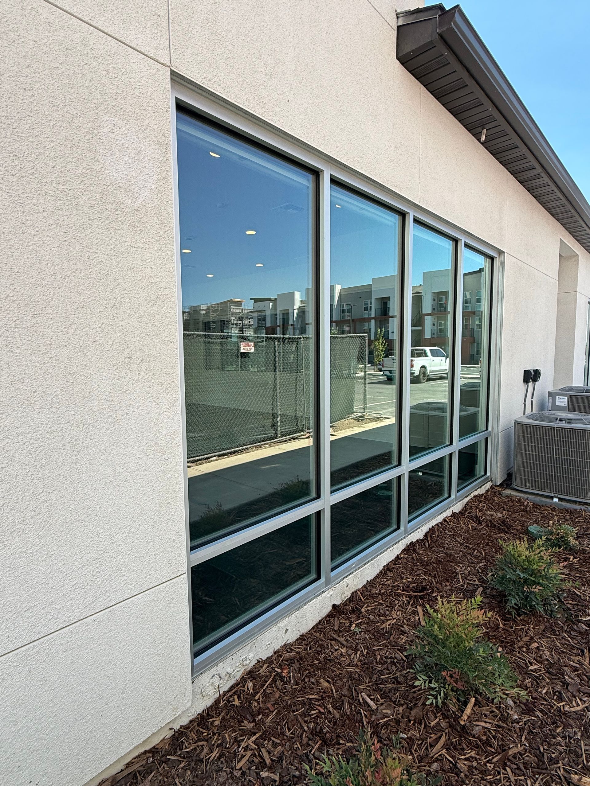 Glass storefront entrance with large windows and a sidewalk outside at sunset