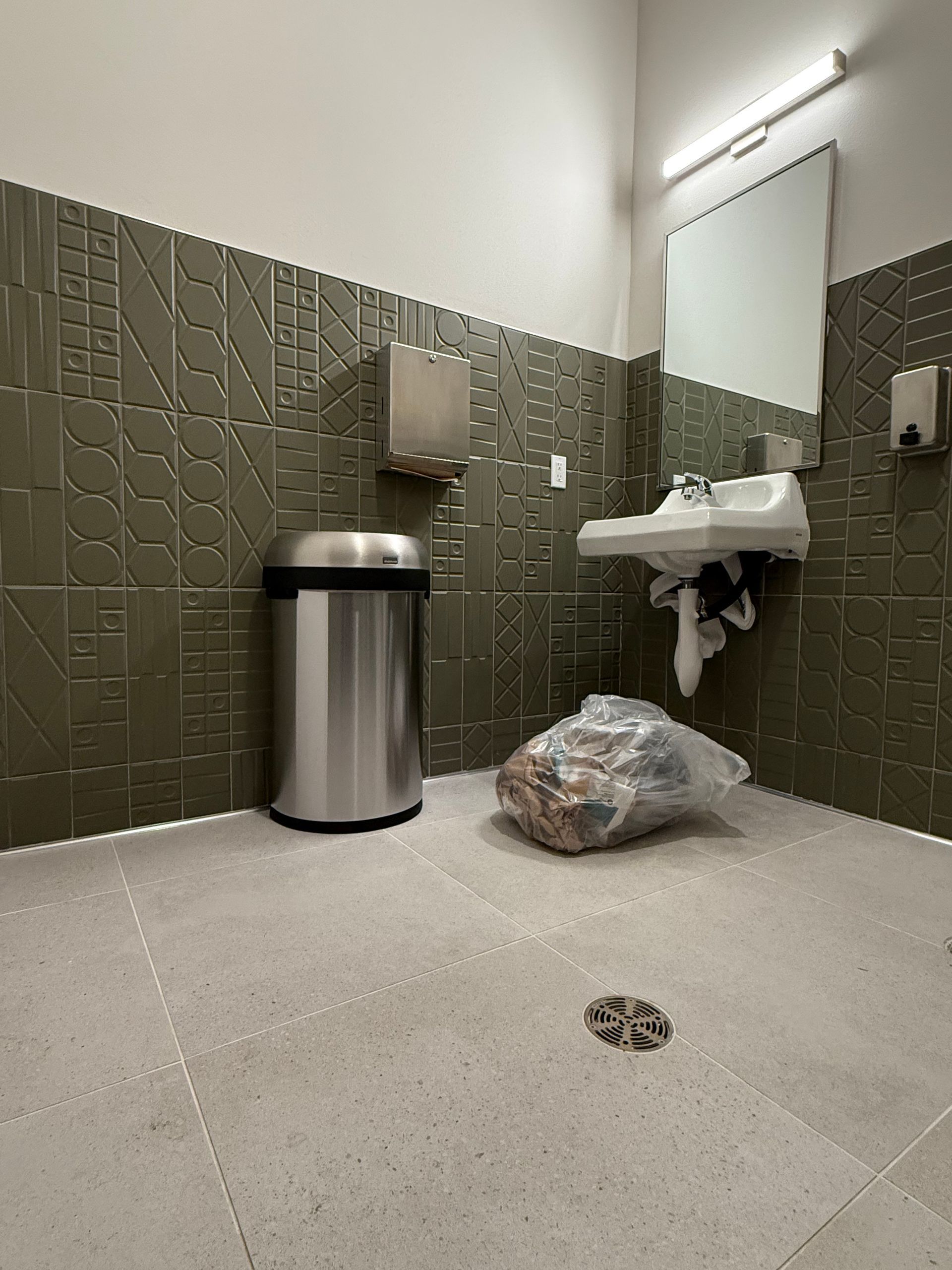 Small break room with a round table and chairs, sink, cabinets, and a trash can by the wall.