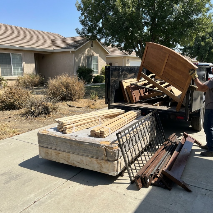 Old furniture and wood piled in a pickup truck and driveway outside a suburban house