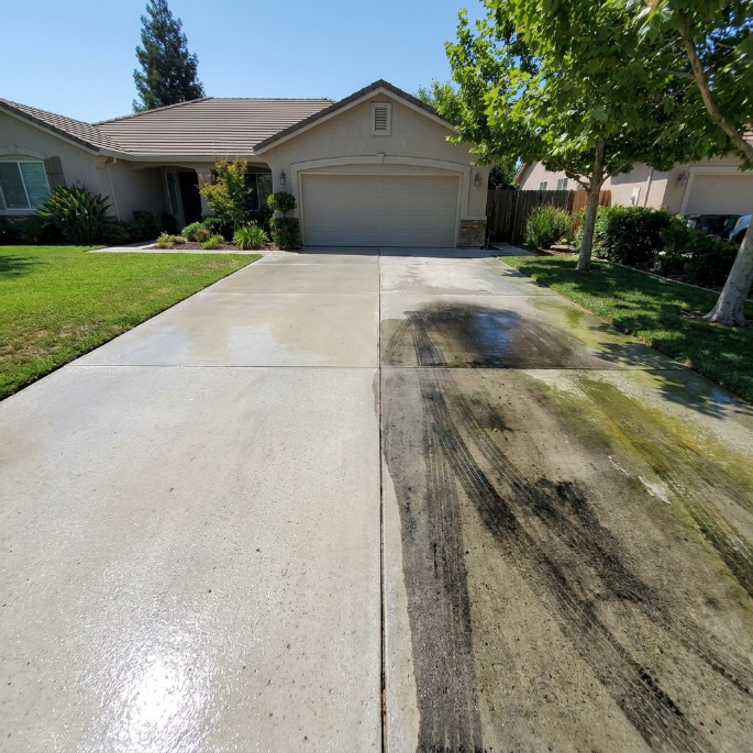 Residential driveway with a dark stain or residue near the garage on a sunny day
