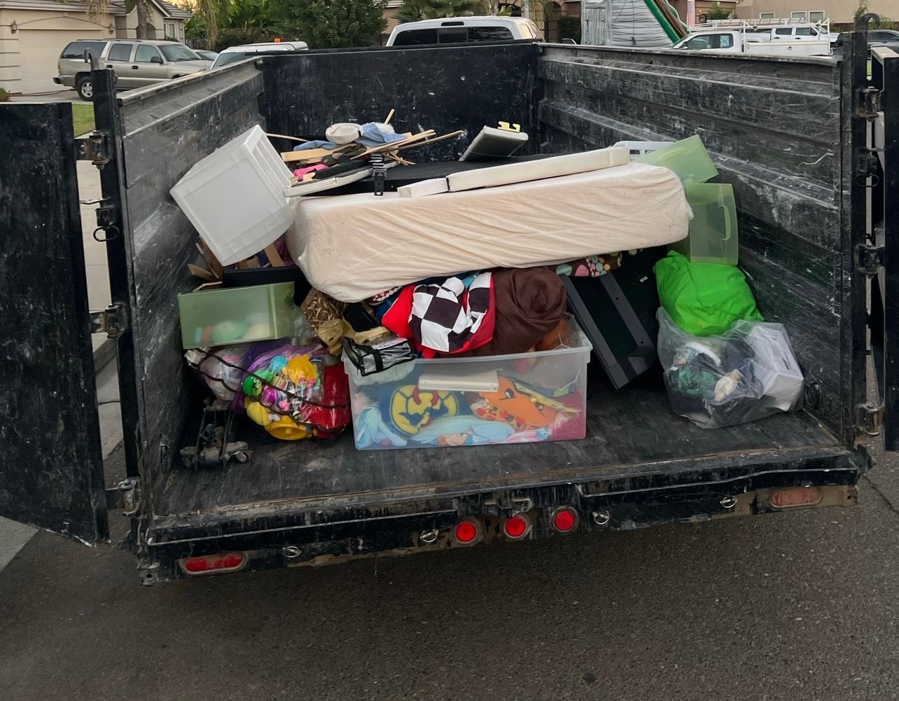 A trailer piled with trash, including a mattress, boxes, bags, and scattered debris.