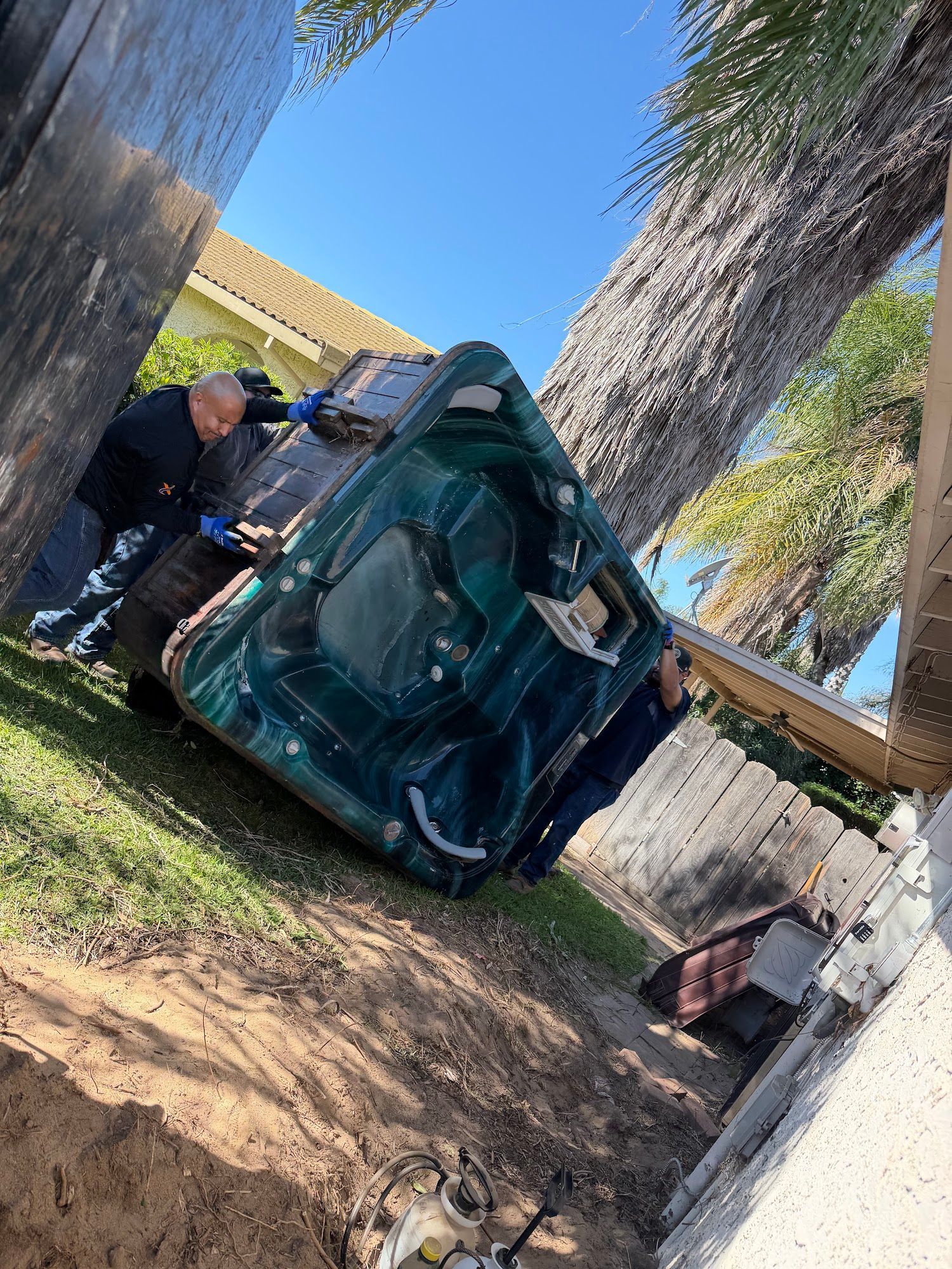 Blue tent/tarp shelter collapsed between trees, with a person standing nearby in a yard.