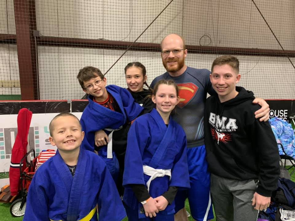 a man in a superman shirt poses with a group of kids