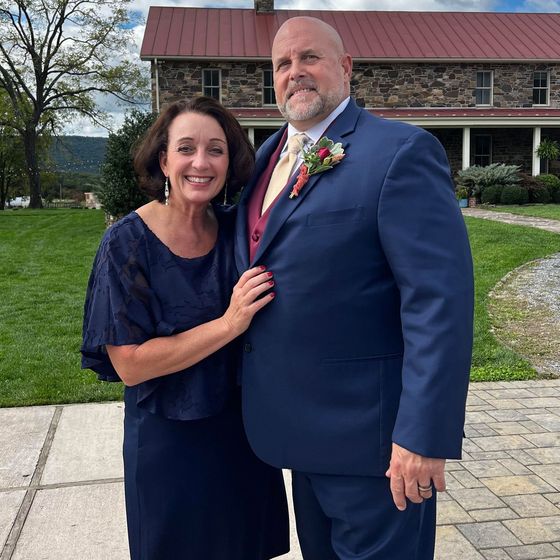 a man and woman posing for a picture in front of a stone building