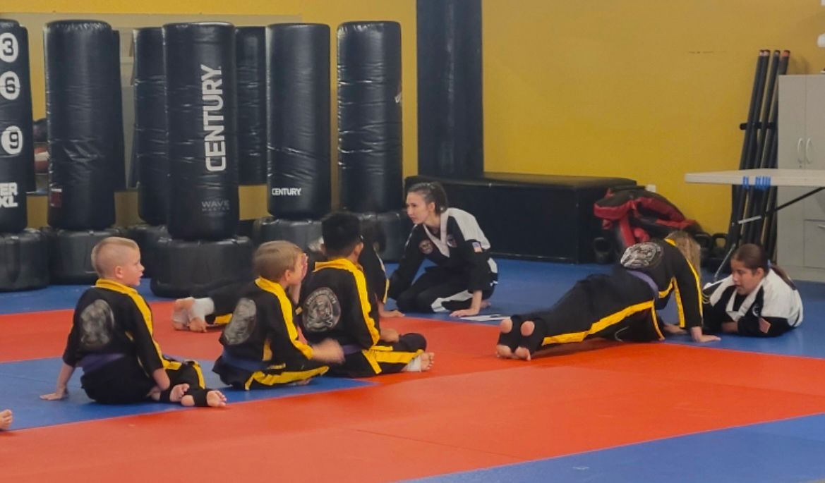 a group of young children are sitting on a mat in a gym .
