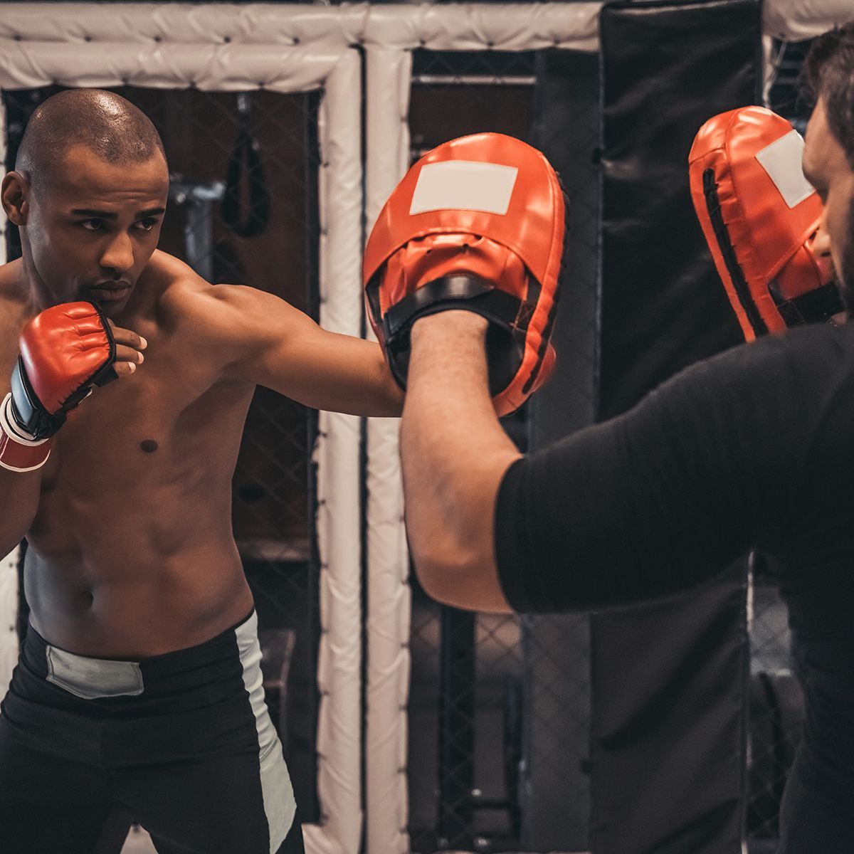 a man wearing boxing gloves is practicing with another man