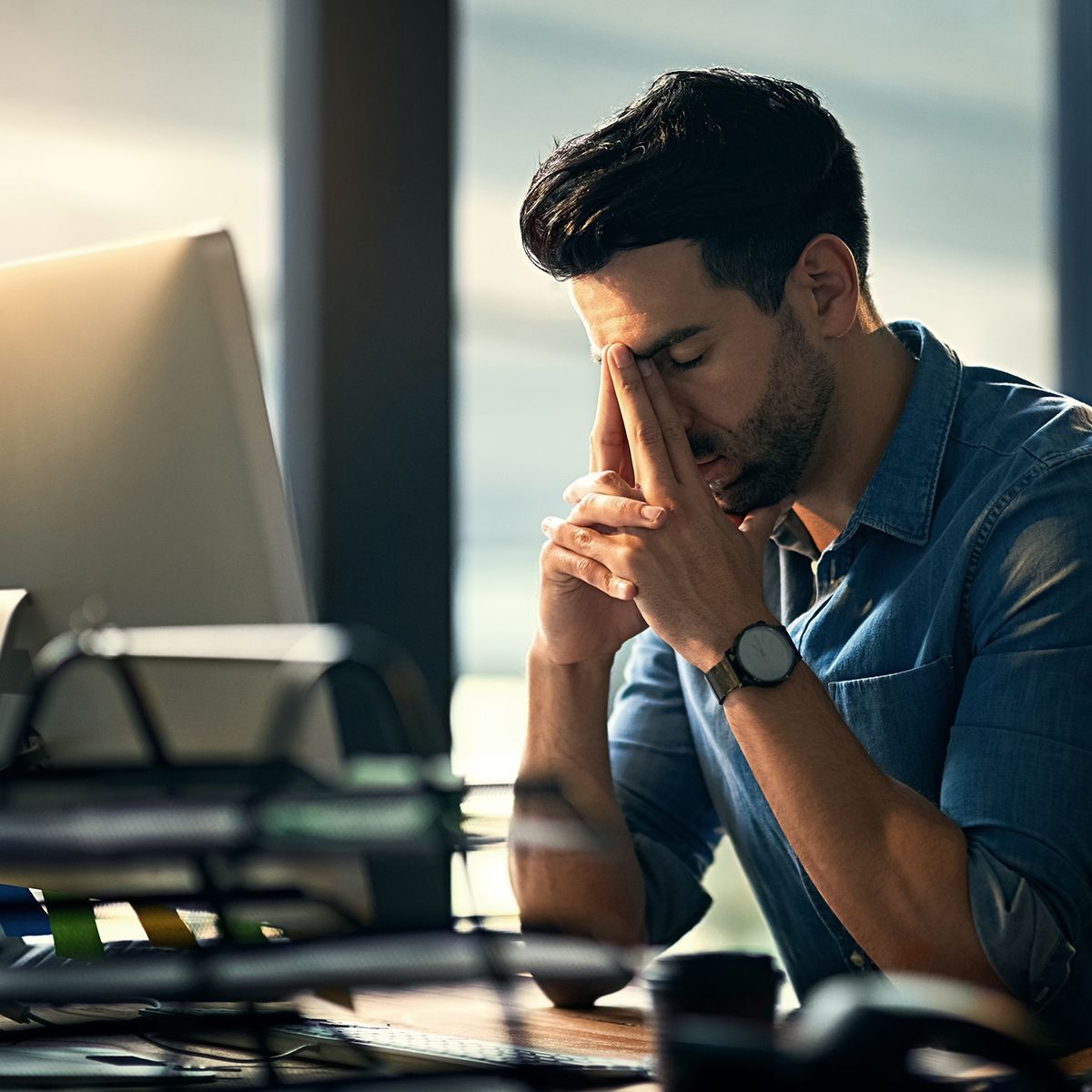a man sitting at a desk with his head in his hands