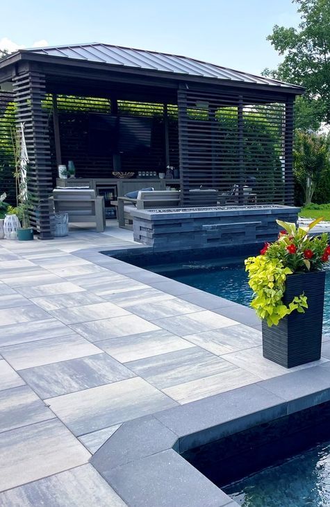 A patio with a gazebo and a swimming pool in the background.