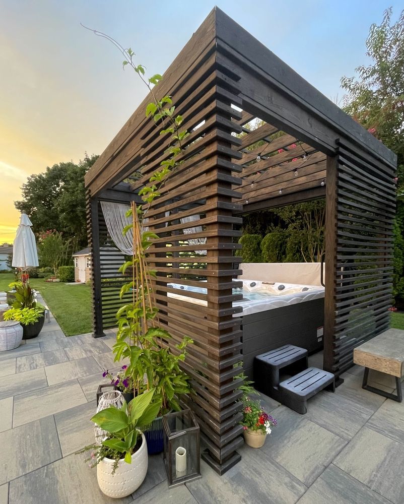 A wooden gazebo with a hot tub inside of it.