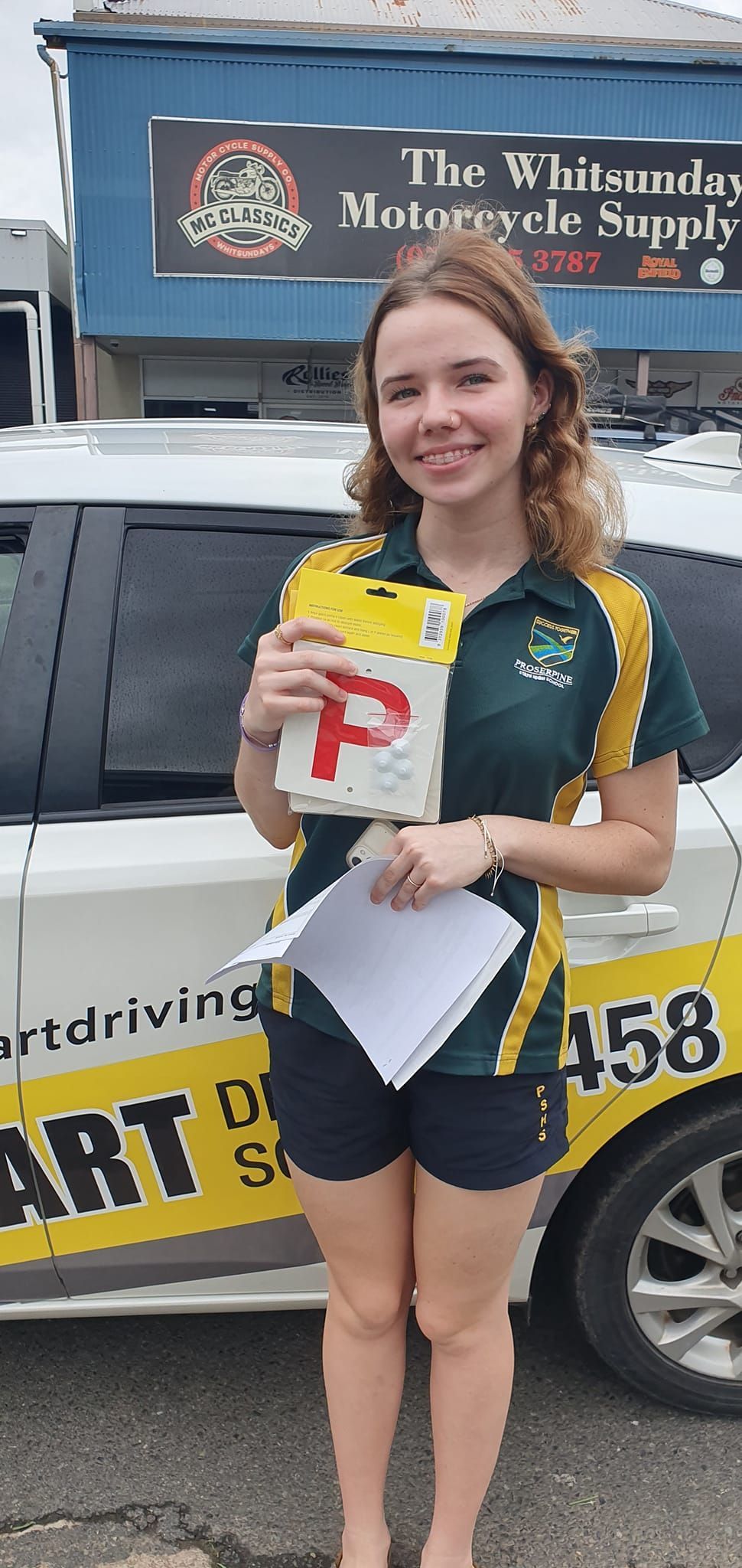 Young Person Holds a a License Next to a White Car — Top Start Driving School (Whitsunday) In Airlie Beach, QLD