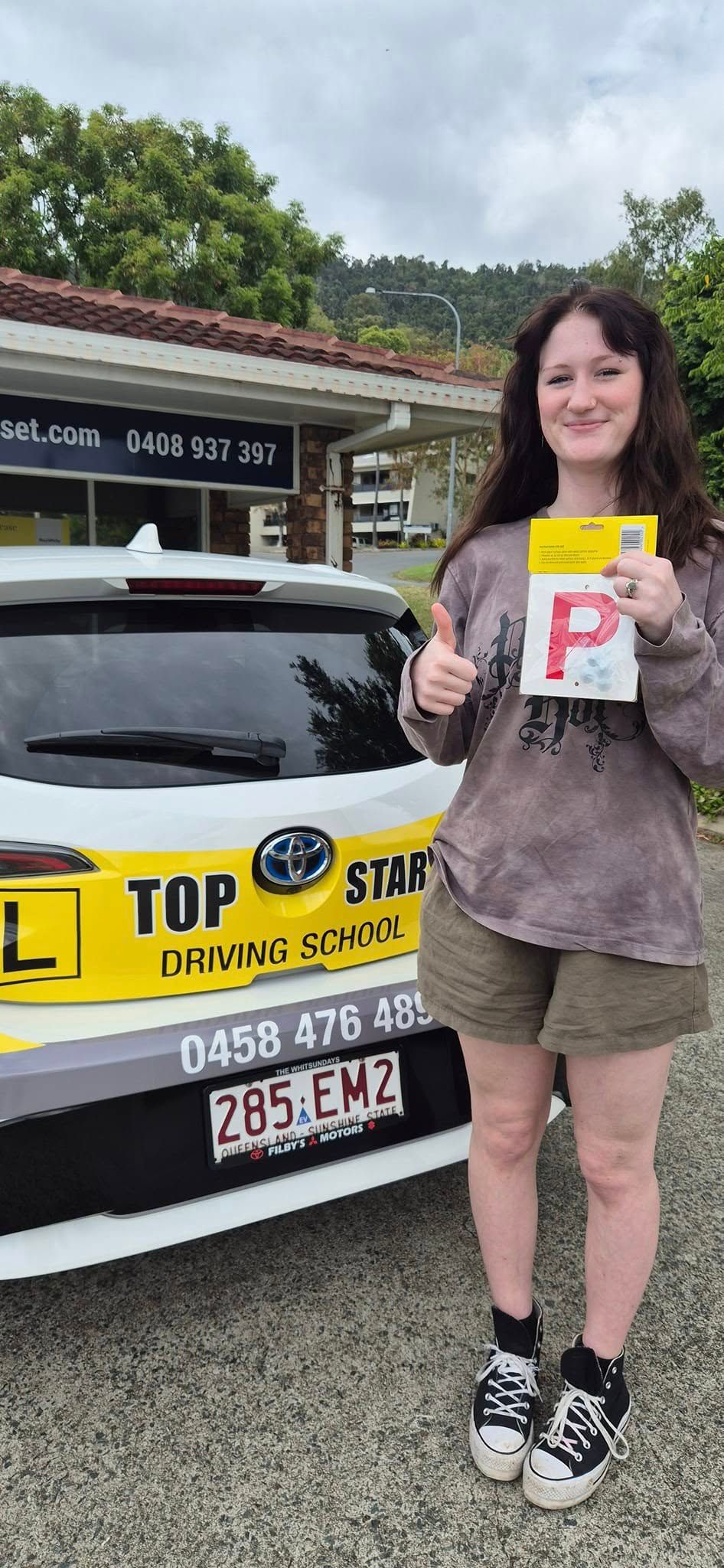 Woman Holding a P-plate, Giving a Thumbs Up — Top Start Driving School (Whitsunday) In Airlie Beach, QLD