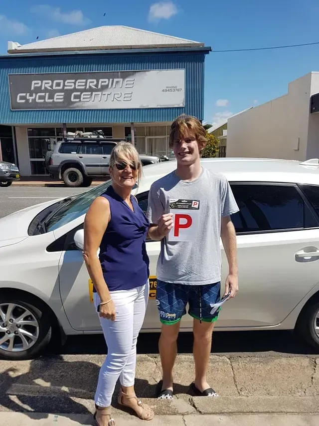 Young Person Holding a P Plate in Front of a Car — Top Start Driving School (Whitsunday) In Airlie Beach, QLD