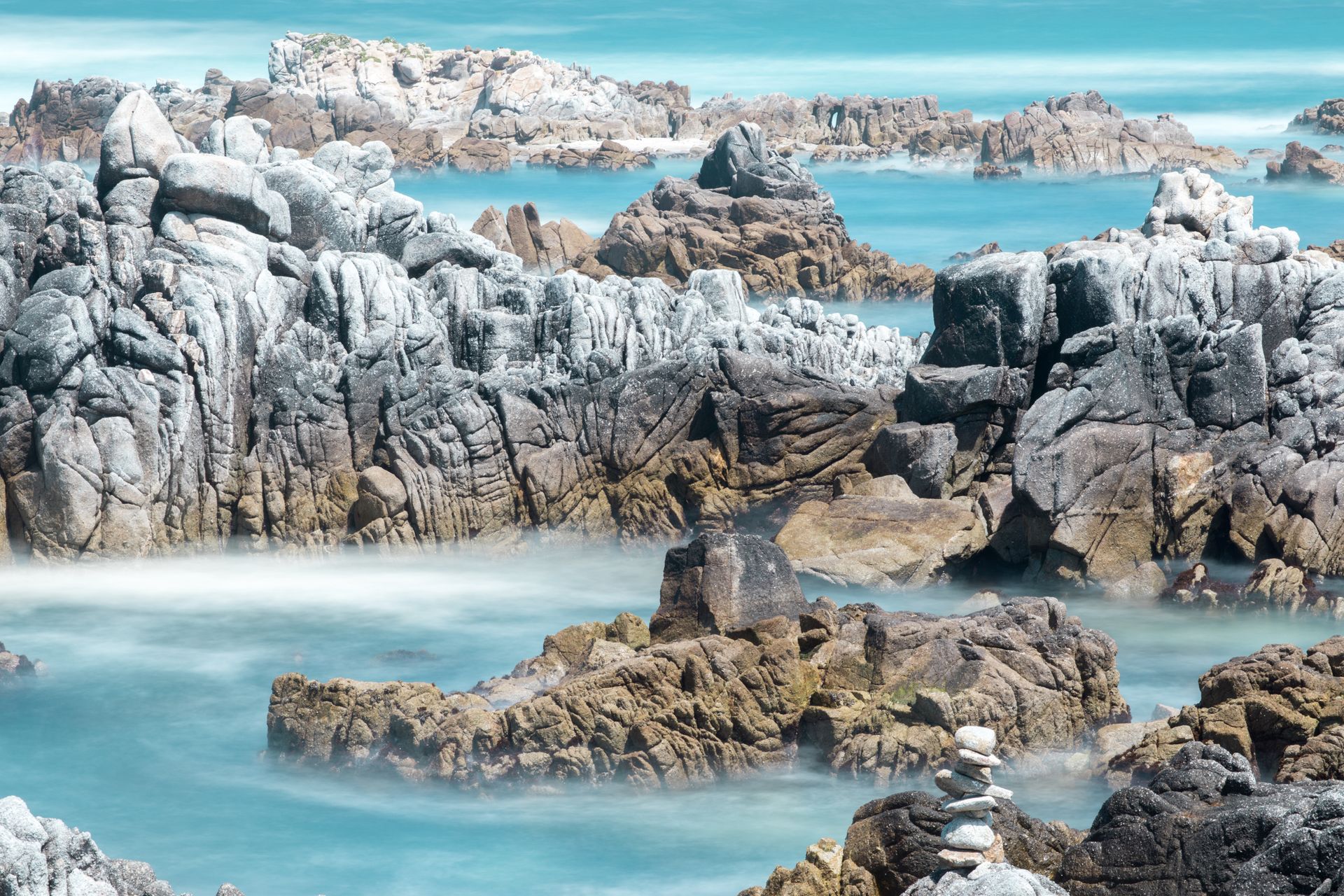 Rocky shoreline with pale stone outcrops and turquoise sea under a clear sky