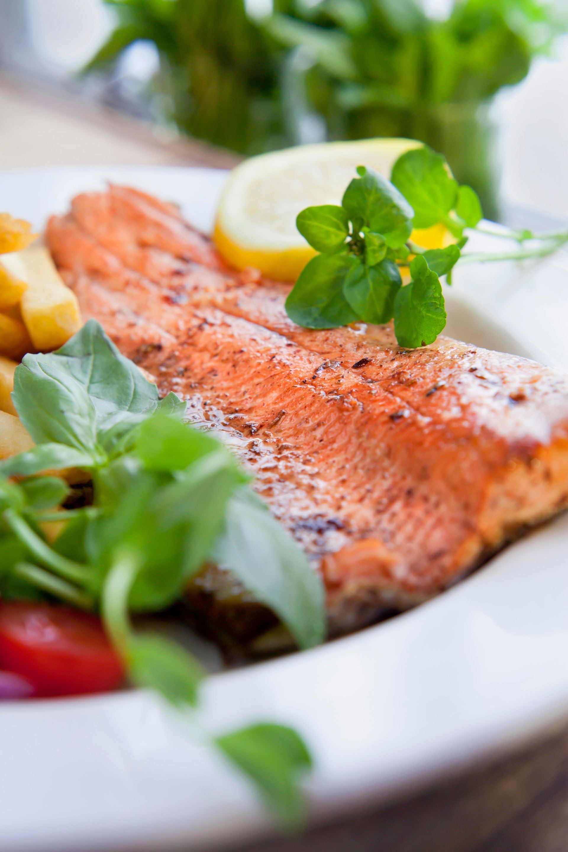 Grilled salmon fillet with lemon and greens on a white plate