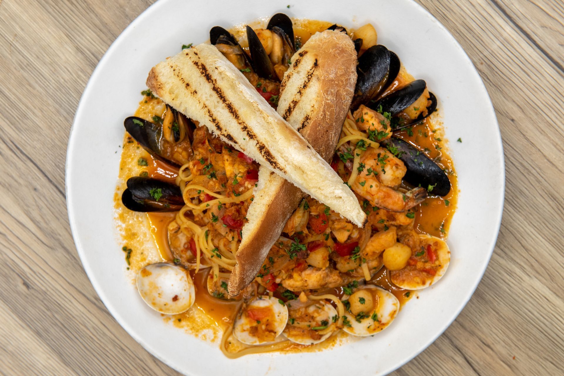 Seafood pasta with mussels, shrimp, and grilled fish on a white plate