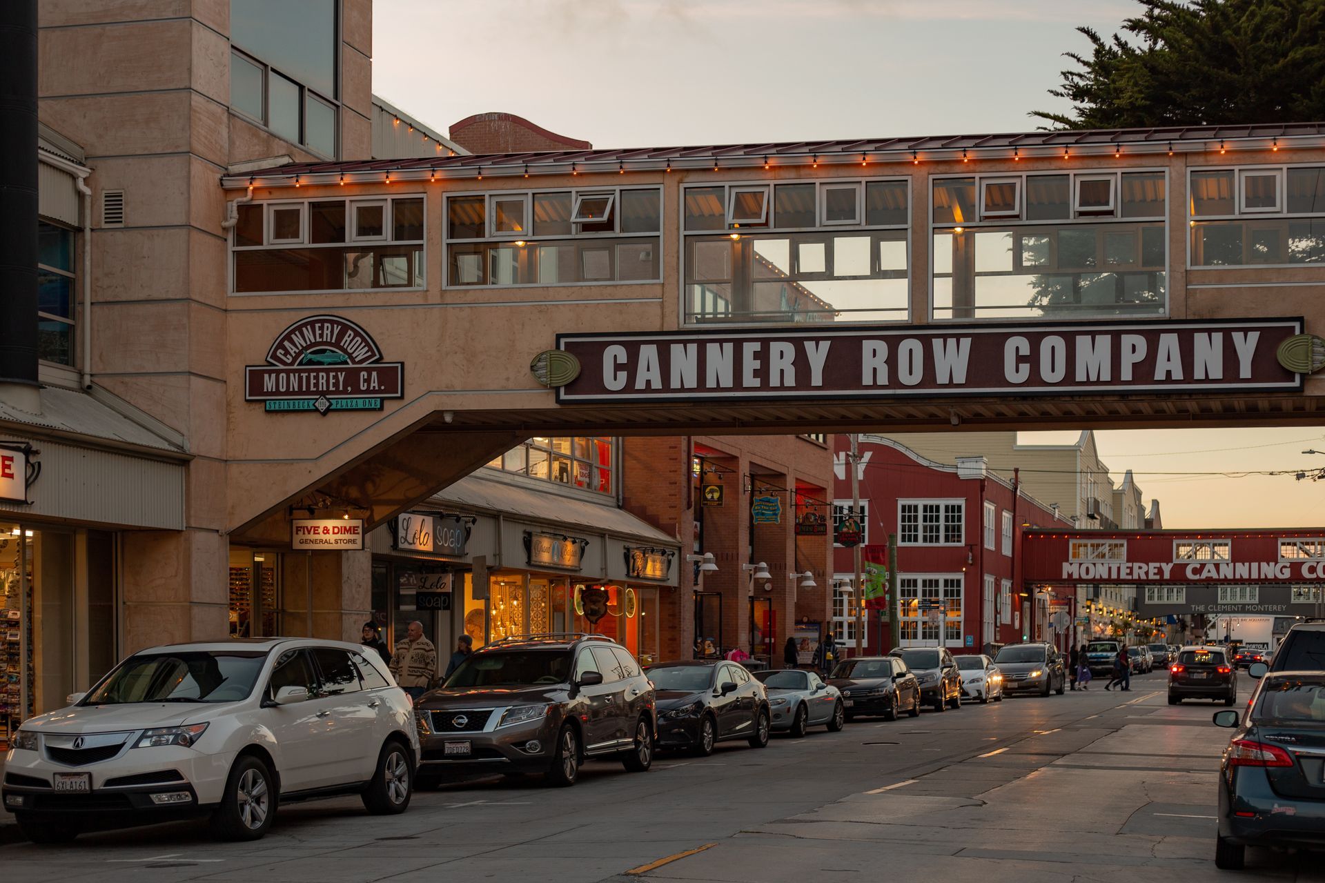 Street scene under Cannery Row Company sign with parked cars and evening light.