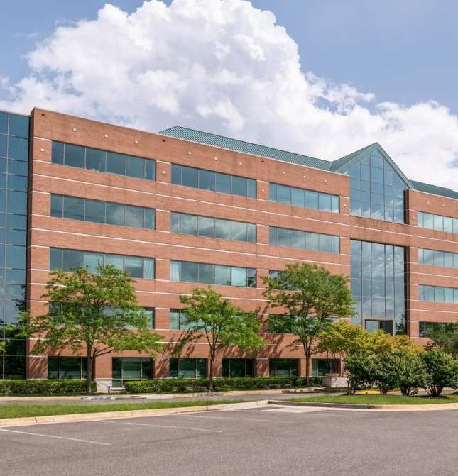 Modern brick office building with large windows and trees in front