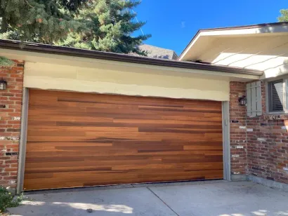 Wooden garage door under a cream awning beside a brick house exterior