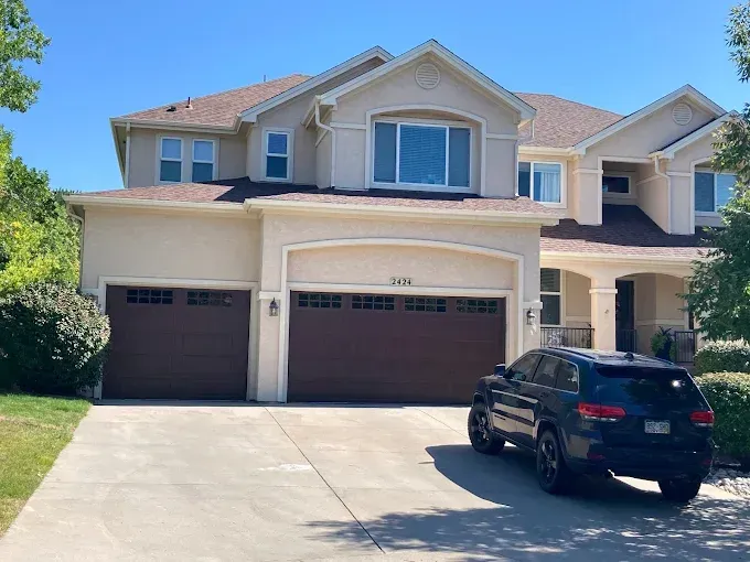 Suburban two-story house with three-car garage and a black SUV parked in the driveway