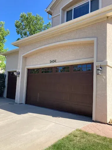 Suburban house exterior with a beige garage, driveway, and blue sky above