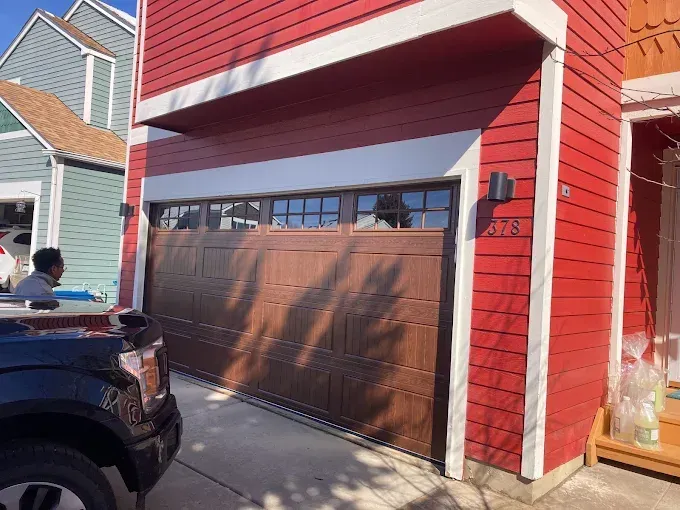Red garage door on a house with white trim and a black SUV parked in front