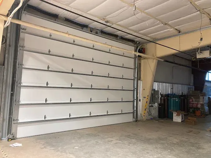 Large white roll-up garage door inside an industrial warehouse space
