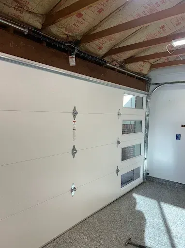 White garage door with windows in a clean garage interior under exposed ceiling beams.