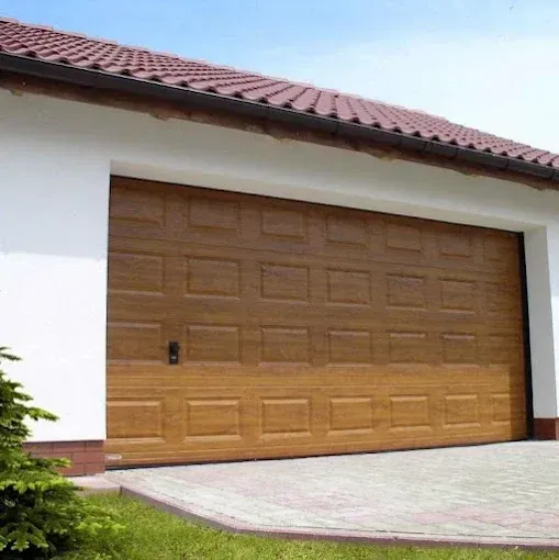 Closed wooden garage door on a white house with a red tiled roof and paved driveway