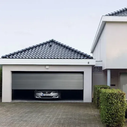 Modern house with a gray tiled garage, partially closed door, and a car parked inside.