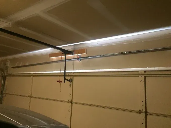 Garage interior with closed sectional door and overhead metal tracks on a beige wall.