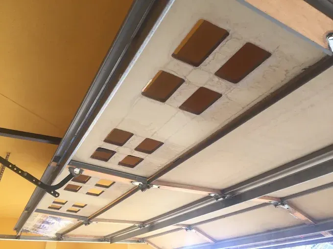 Interior view of a garage door with metal rails and white panels, lit by warm ceiling light