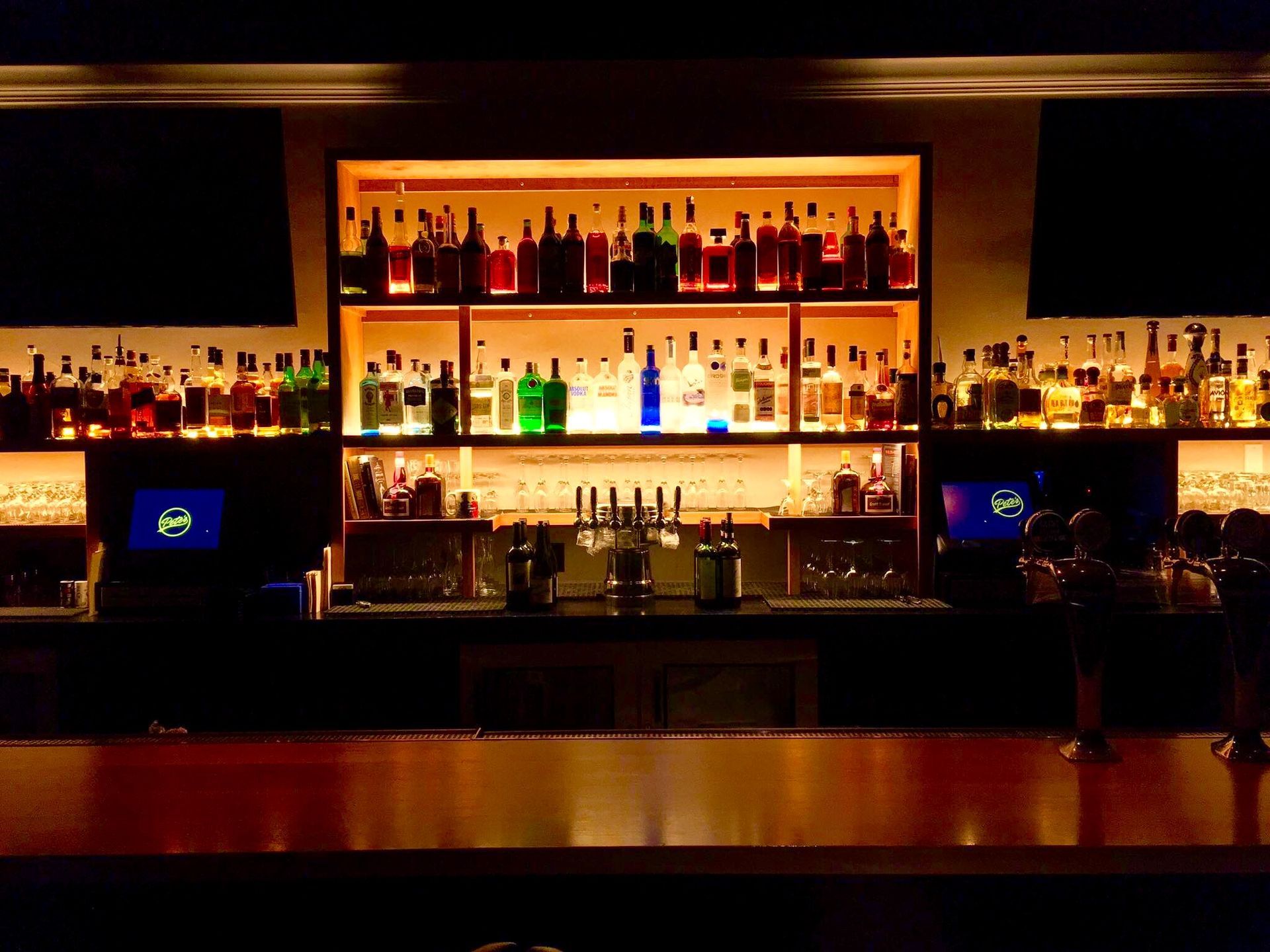 A bar with a lot of bottles of alcohol on shelves