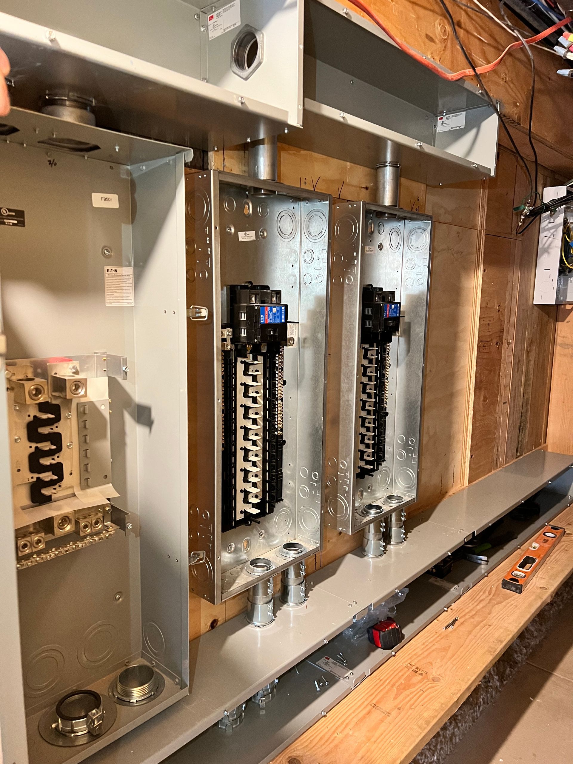 Three electrical boxes are sitting on a wooden wall.
