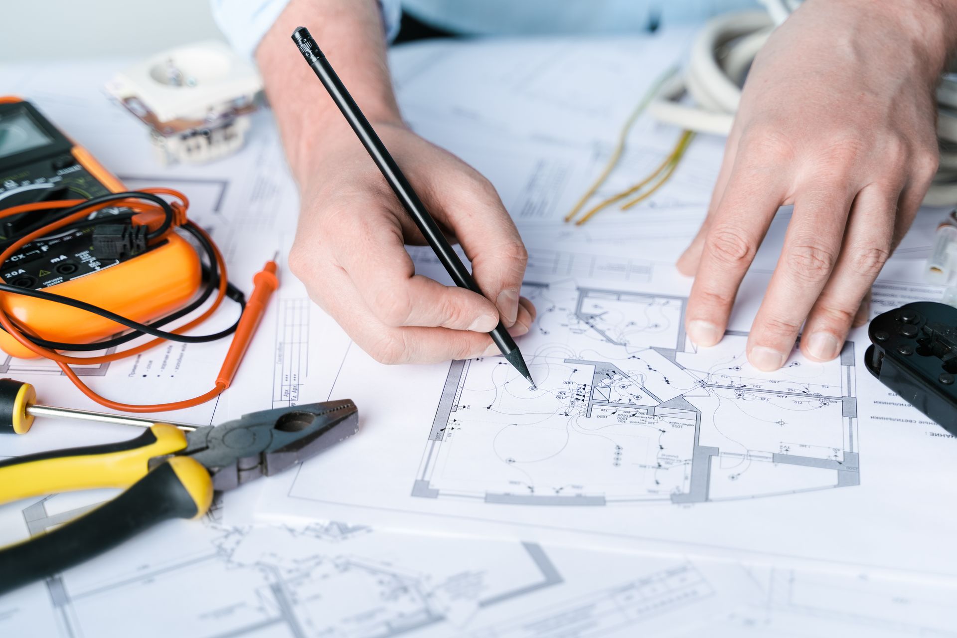 A person is writing on a blueprint with a pencil.