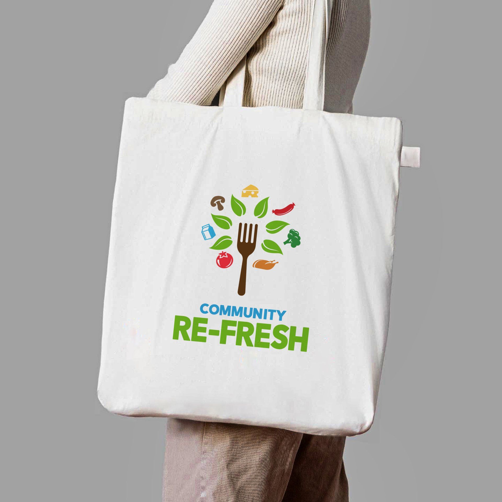 A person is holding a white tote bag that says community re-fresh