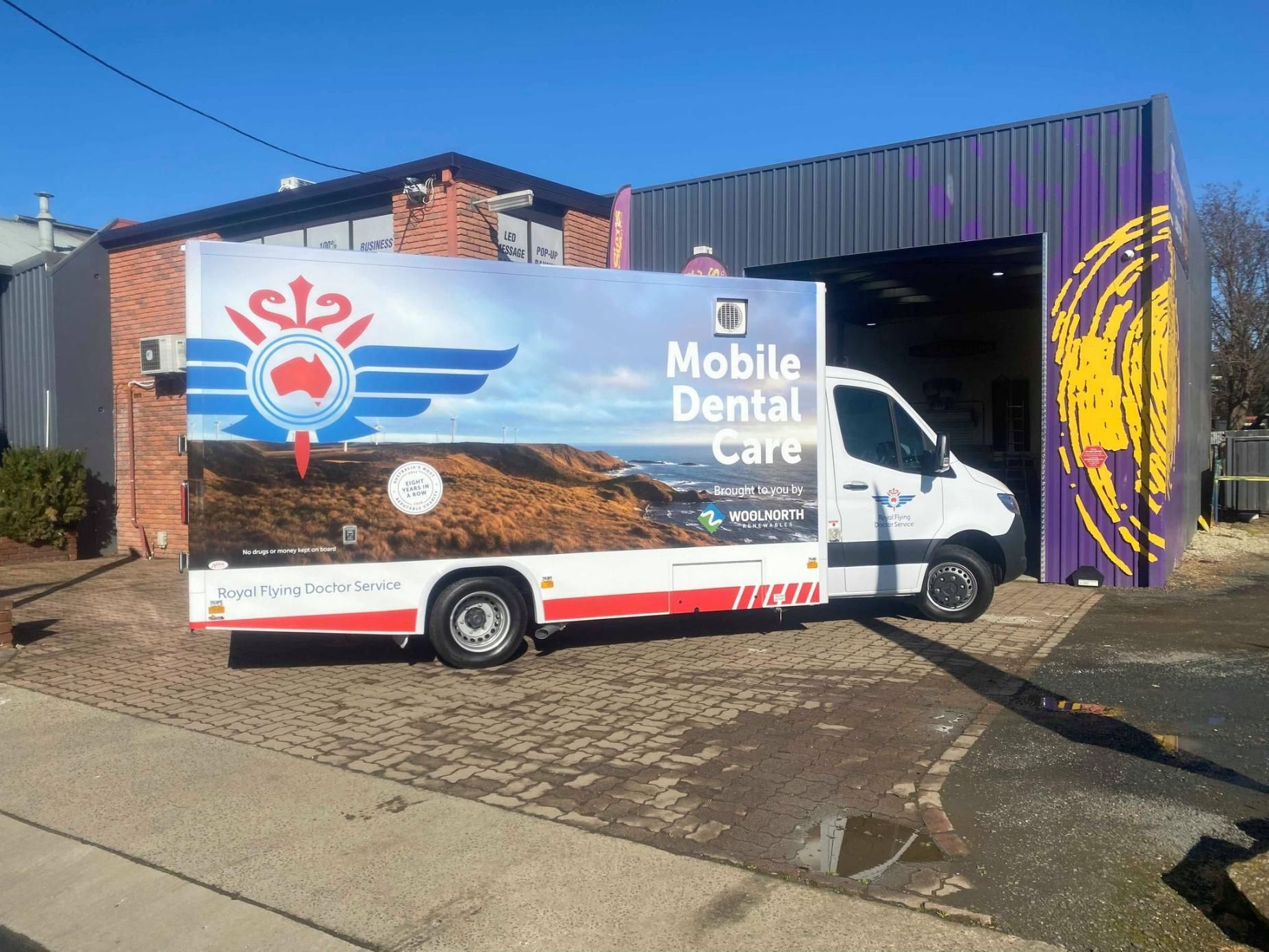 A mobile dental care truck is parked in front of a building.